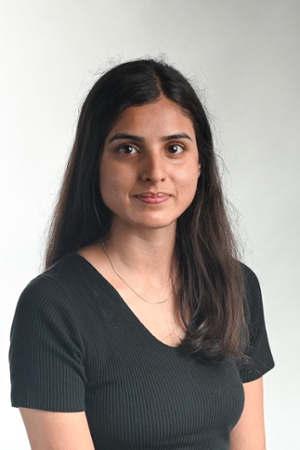 faintly smiling woman with long dark hair down back and over left shoulder wearing a black v-neck top and silver necklace