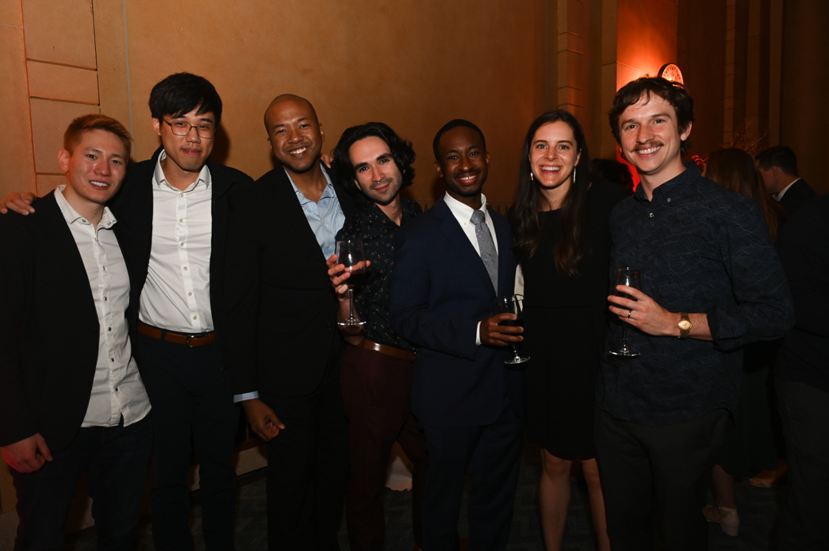 people smiling and standing in a row wearing party clothes