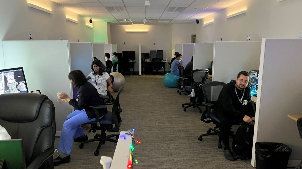 large room of cubicles where people are sitting and some are working and some are chatting