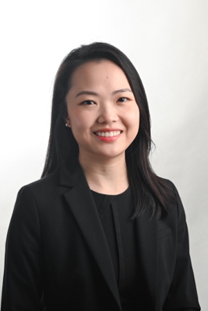 smiling woman with long black hair falling to below shoulders wearing a black suit jacket over a black top