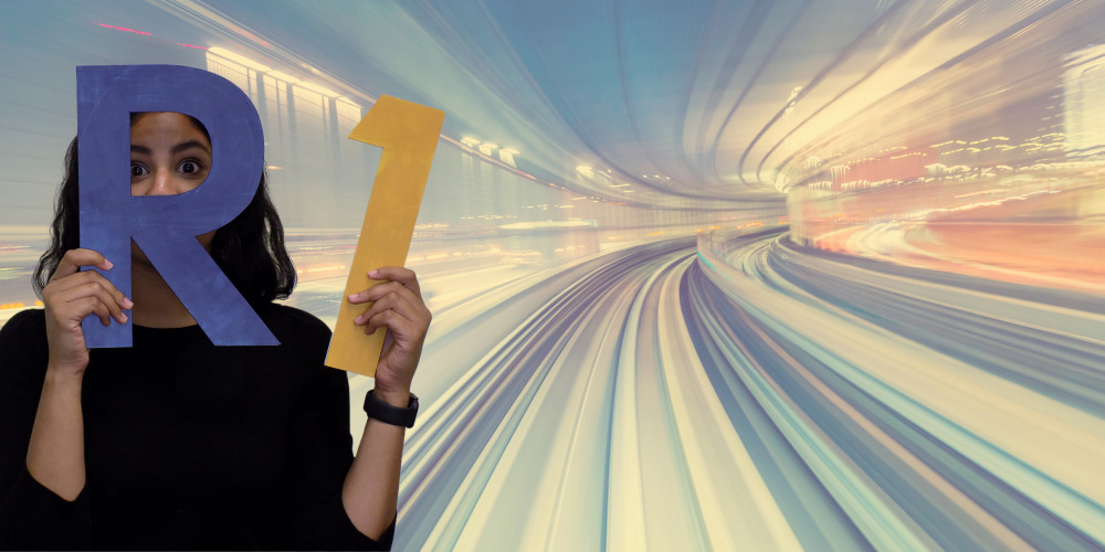 woman holding and peering through a blue letter R and holding a gold number 1 with a background of neon lights in traffic lanes