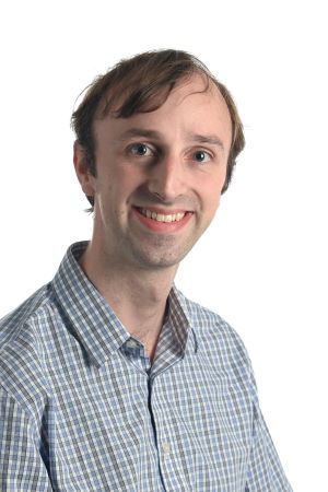 smiling person with light brown hair wearing a blue and grey shirt