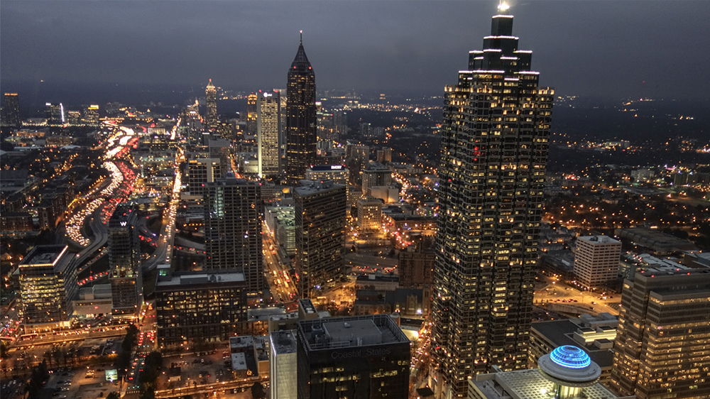 city of Atlanta skyline with tall buildings and large ferris wheel lit up at night