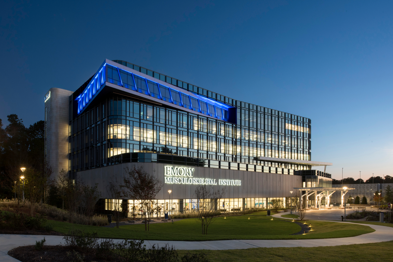 glass and concrete building with grass and winding walkway in front