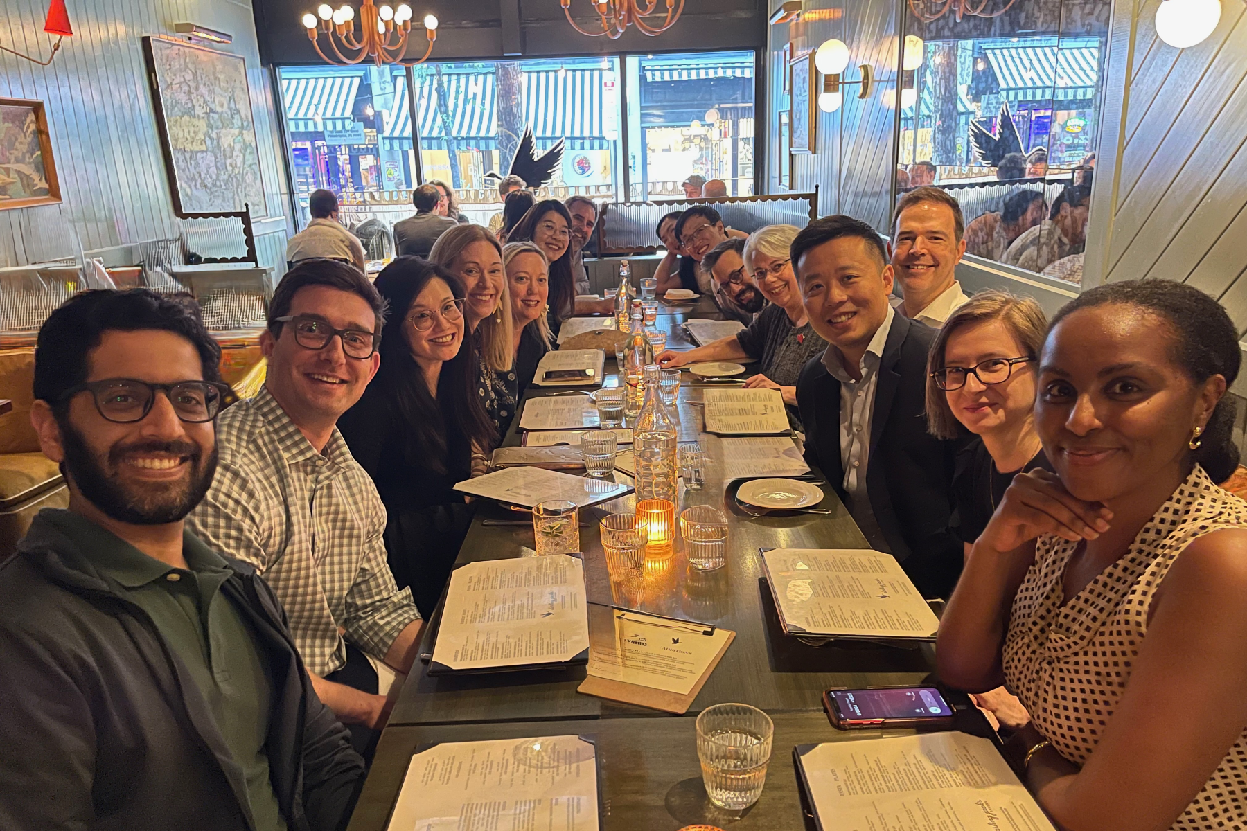 long row of tables with smiling people seated on both sides