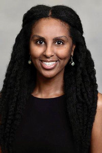 smiling person with long black hair wearing a black top and silver earrings