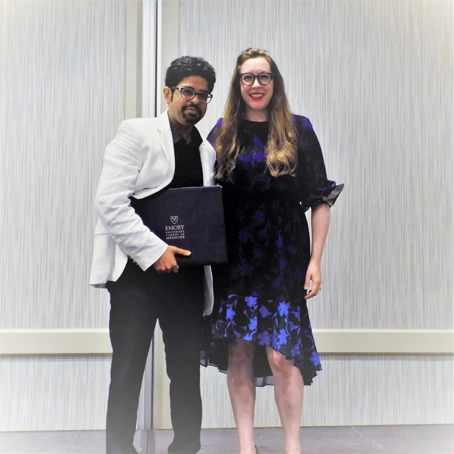 smiling man holding diploma standing with smiling woman holding microphone