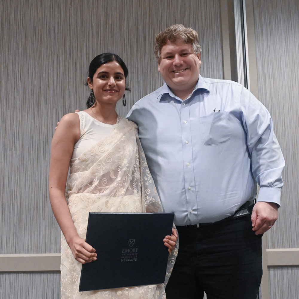 two smiling doctors one holding graduation certificate