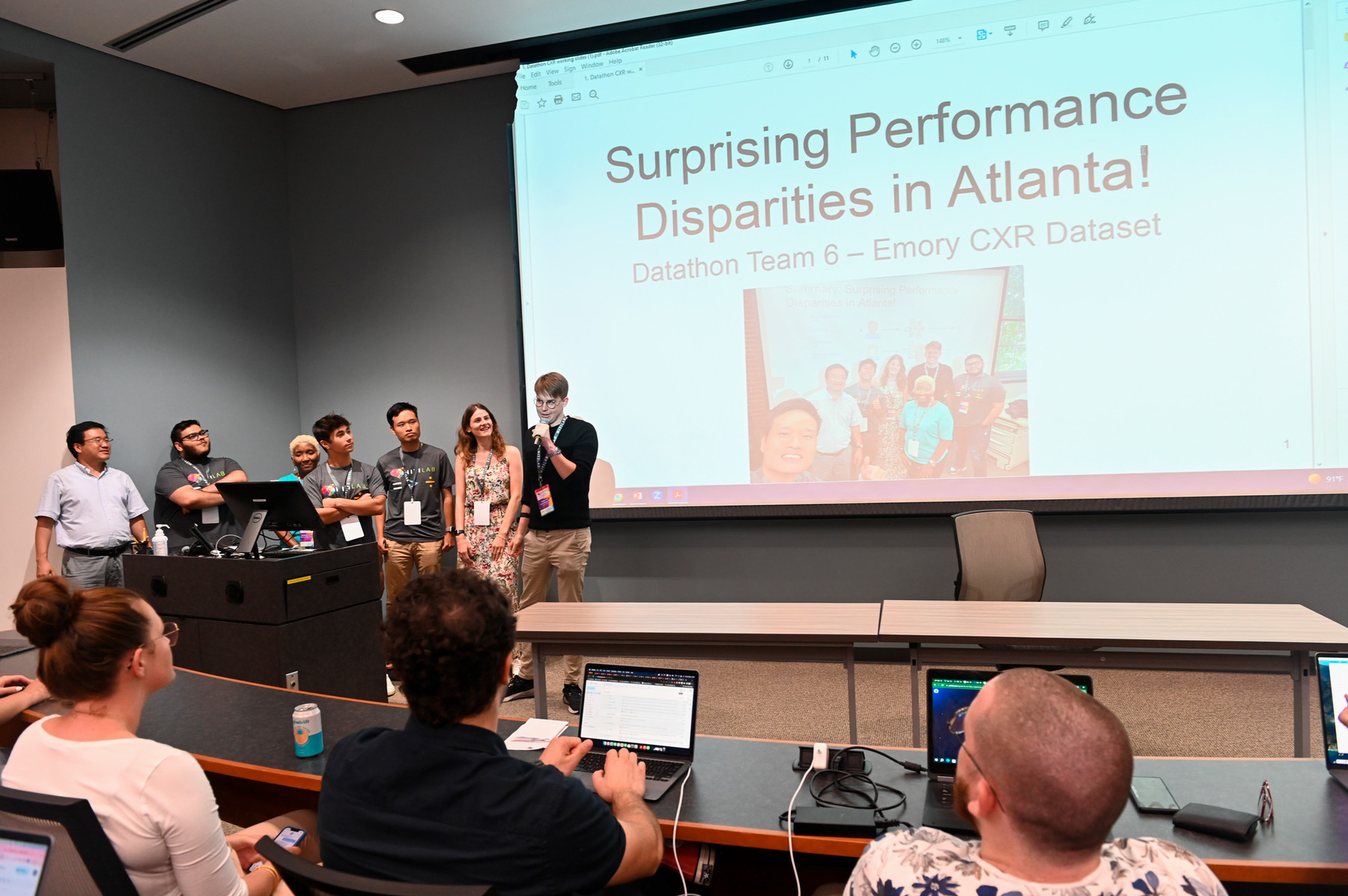 seven people presenting at the front of a classroom