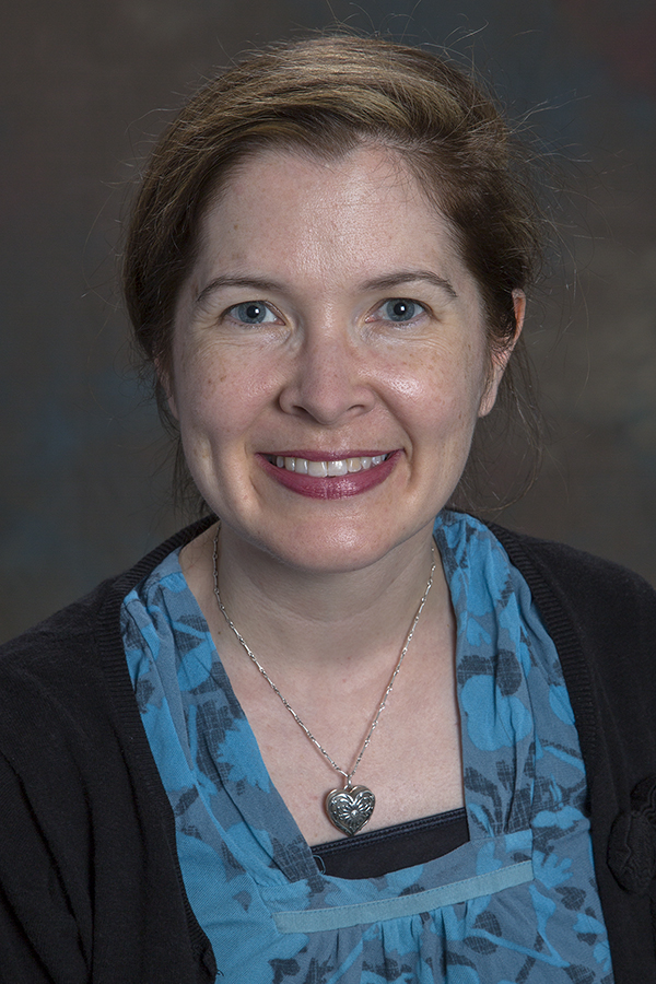 smiling woman with light brown hair pulled away from face and wearing a blue shirt