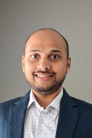 smiling person wearing a blue suit jacket over a light shirt