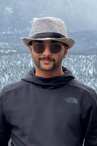 smiling person wearing glasses and a hat
