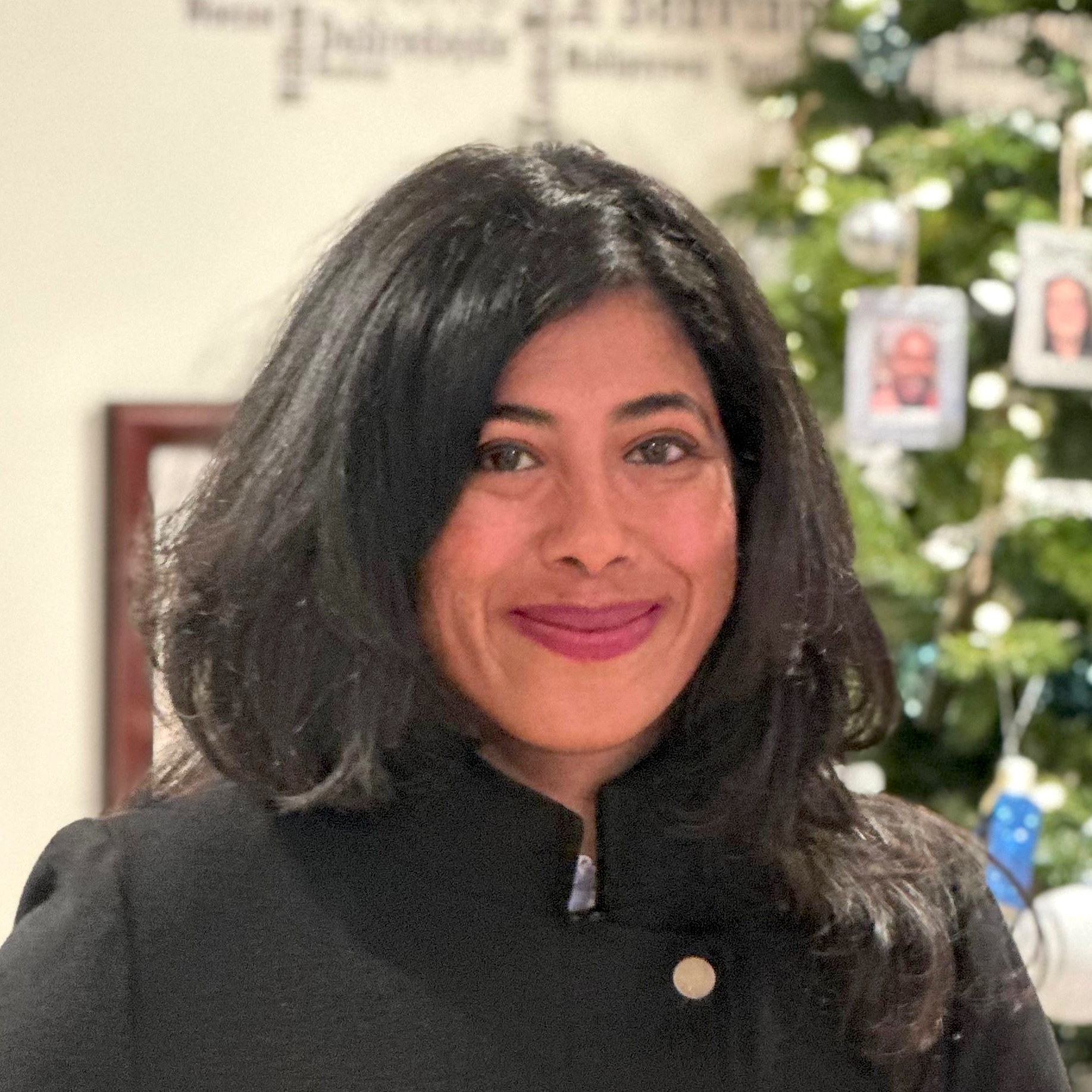 headshot of woman with christmas tee in background