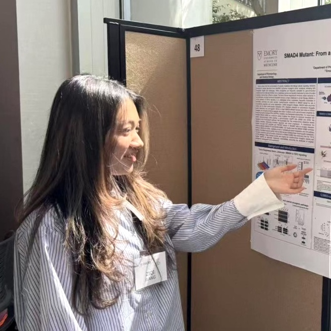 woman pointing at poster board at a scientific conference