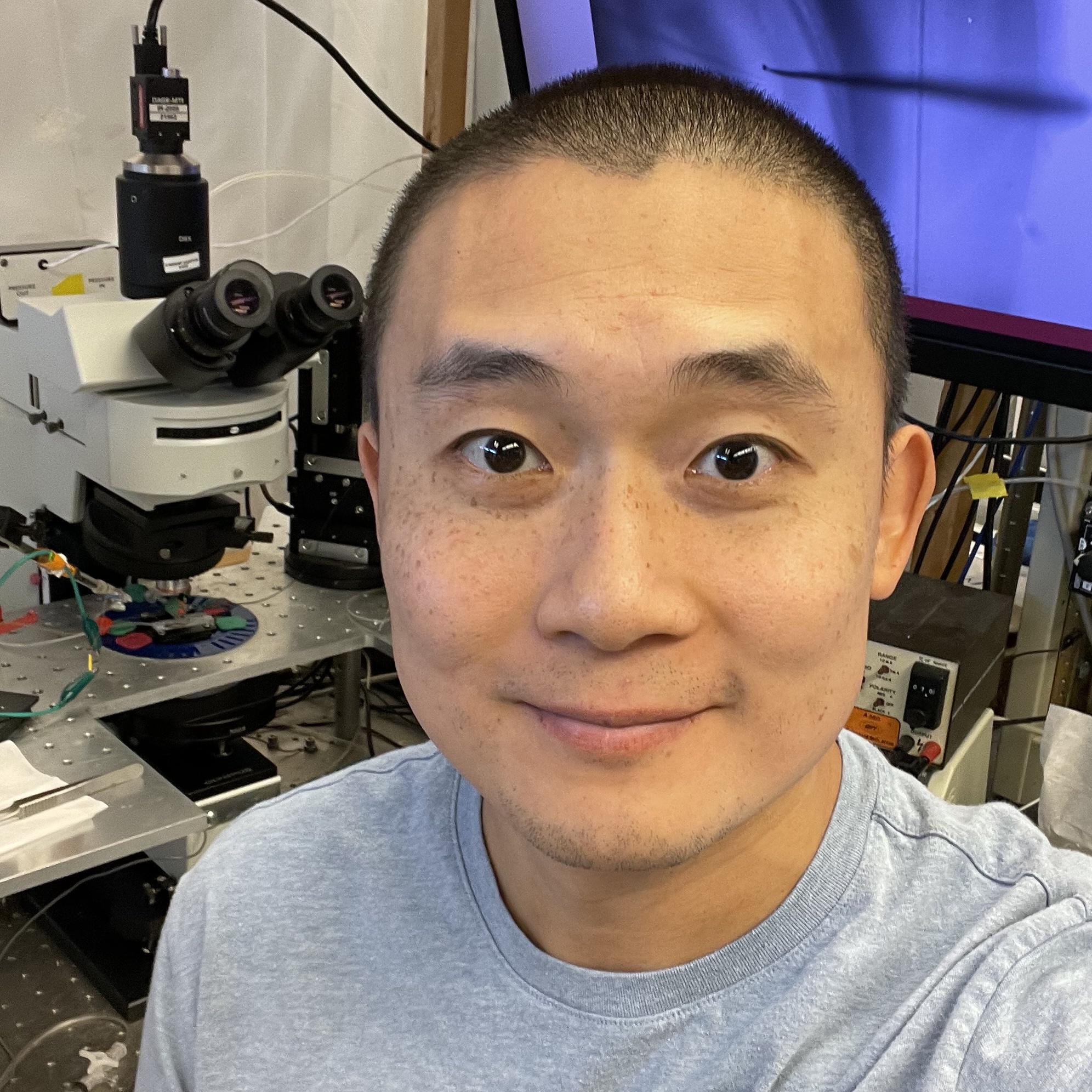 headshot of man sitting in front of microscope