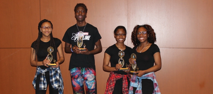 Four undergrad students holding trophies