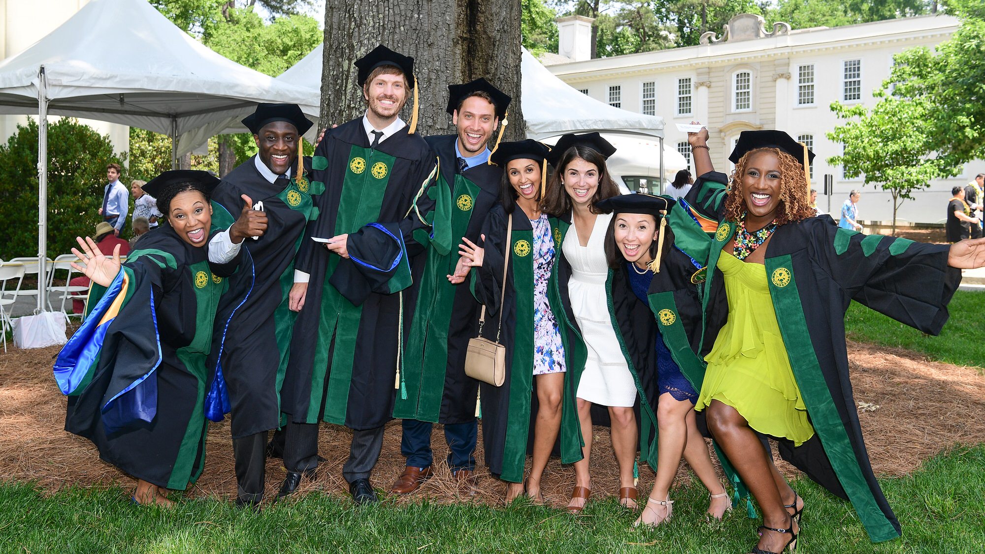 Eight students posing after graduation in their robes