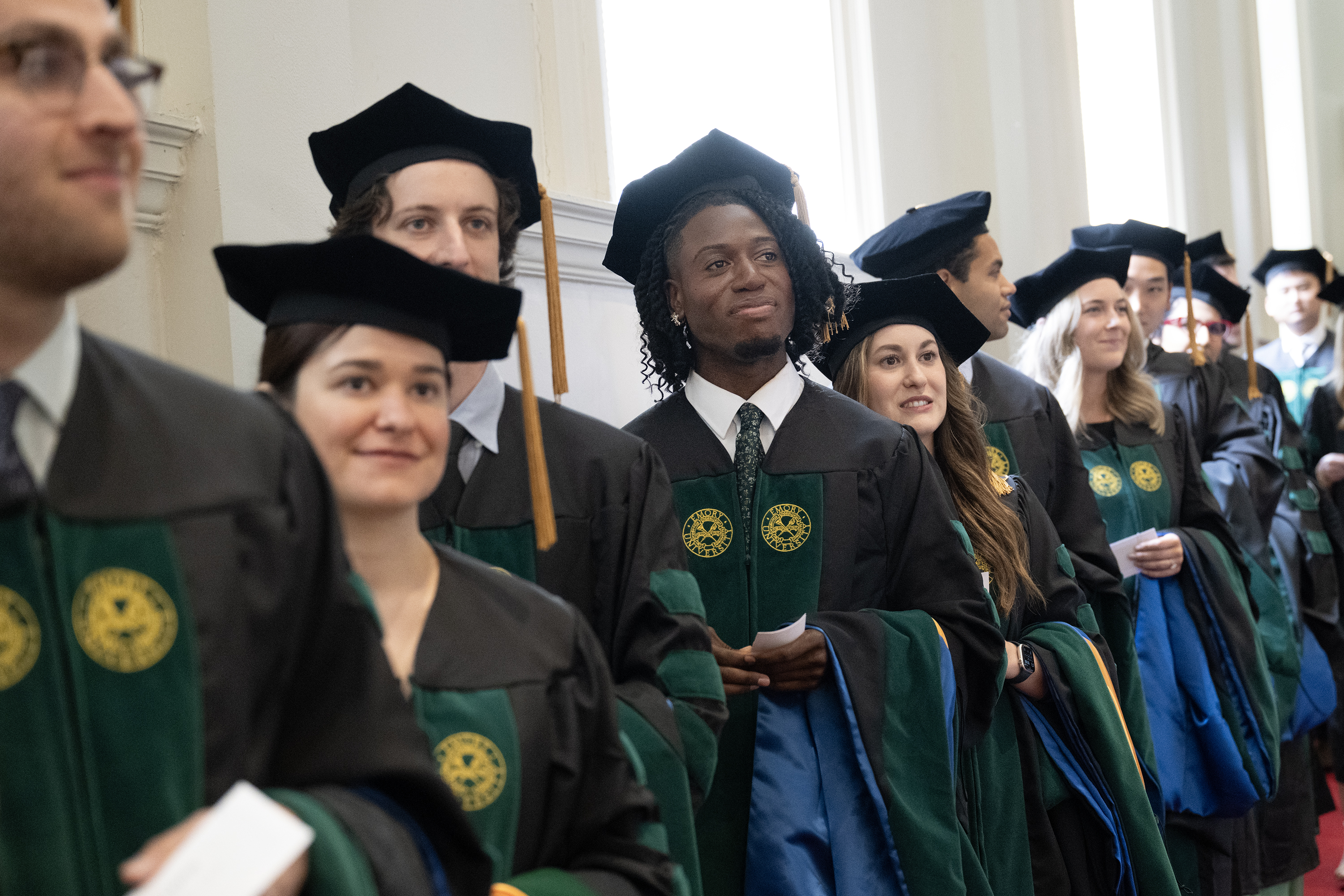 a large group of graduates in regalia in a line indoors