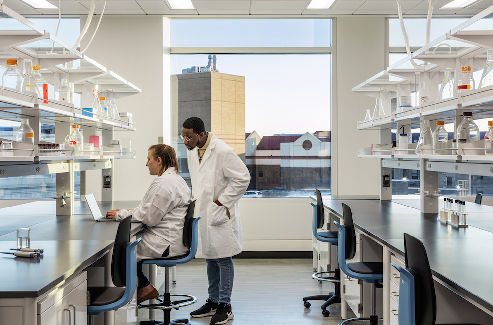 Two scientists assist each other in the lab