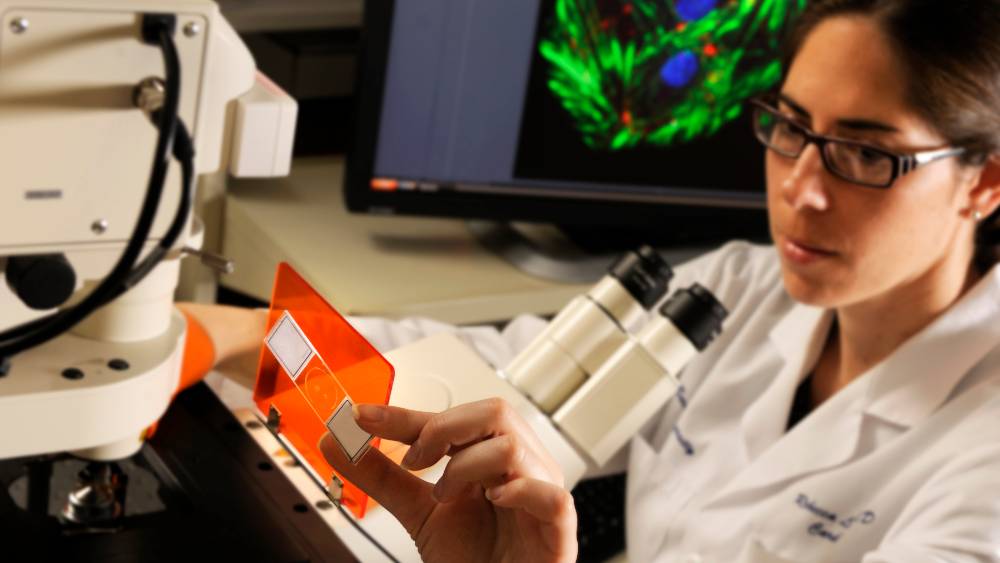 scientist looking at a mircoscope slide